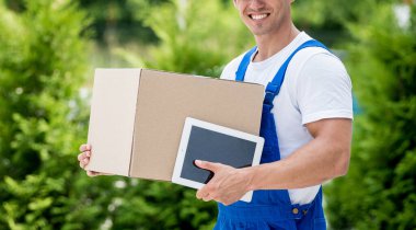 Genç teslimatçı elinde bir karton kutu tutuyor.