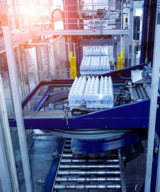 İçecek fabrikasında ambalaj hattı için modern bağlama ve taşıma makinesi.