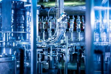 Modern içecek fabrikasında otomatik doldurma makinesi plastik PET şişelerine su doldurur.