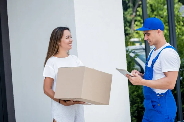 Young courier delivering goods to a young woman at home