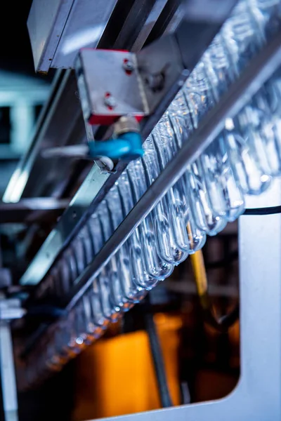 Máquina de enchimento automático derrama água em garrafas PET de plástico na moderna fábrica de bebidas. — Fotografia de Stock