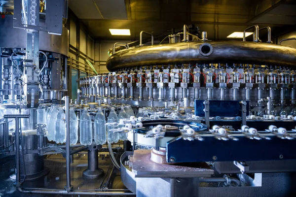 Máquina automática de llenado vierte agua en botellas de plástico PET en planta de bebidas moderna. —  Fotos de Stock