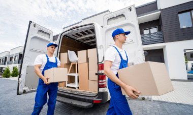 İki nakliye şirketi çalışanı bir minibüse kutu ve mobilya yüklüyorlar..