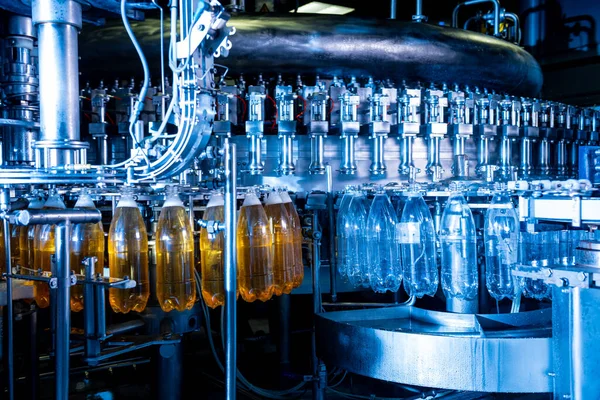 Riempitrice automatica versa acqua in bottiglie di plastica PET in un moderno impianto di bevande. — Foto Stock