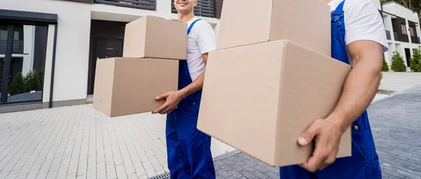 Deux travailleurs de l'entreprise de déménagement déchargeant des boîtes dans la maison de nouveaux clients — Photo