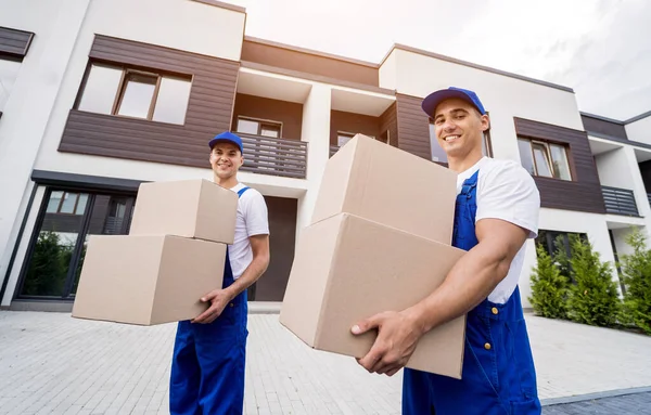 Zwei Mitarbeiter eines Umzugsunternehmens laden Kisten bei Neukunden ab — Stockfoto