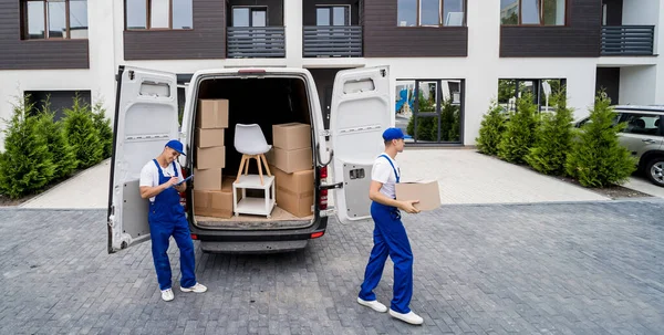 Два працівники компанії з видалення розвантажують коробки та меблі з мікроавтобуса — стокове фото