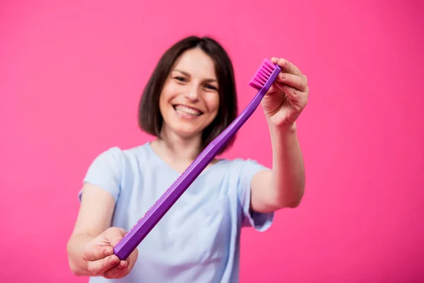 Schöne glückliche junge Frau mit großer Zahnbürste auf leerem rosa Hintergrund — Stockfoto