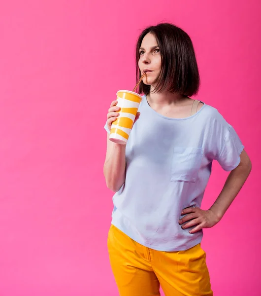 Junge Frau mit empfindlichen Zähnen trinkt kaltes Wasser auf farbigem Hintergrund — Stockfoto