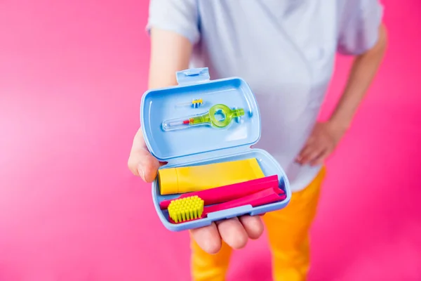 Schöne Mädchen verwendet ein Reise-Set für die Zahnpflege auf rosa Hintergrund — Stockfoto