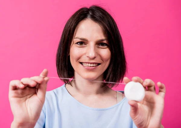 Schöne junge Frau verwenden Zahnseide auf rosa Hintergrund — Stockfoto