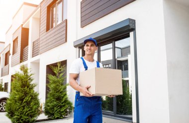 Genç teslimatçı elinde bir karton kutu tutuyor.