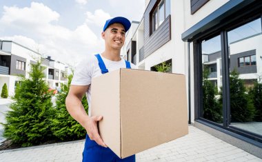 Genç teslimatçı elinde bir karton kutu tutuyor.