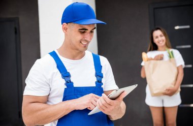 Genç kurye evde genç bir bayana mal getiriyor.