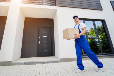 Genç teslimatçı elinde bir karton kutu tutuyor.
