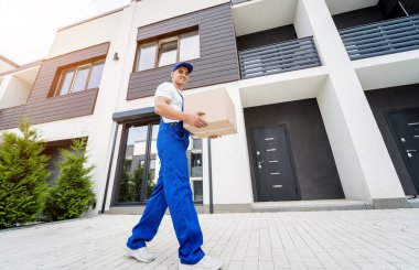 Genç teslimatçı elinde bir karton kutu tutuyor.