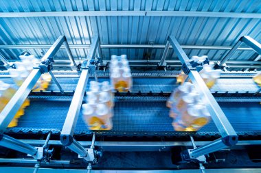 İçecek fabrikasında ambalaj hattı için modern bağlama ve taşıma makinesi.