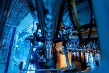 Modern içecek fabrikasında otomatik doldurma makinesi plastik PET şişelerine su doldurur.