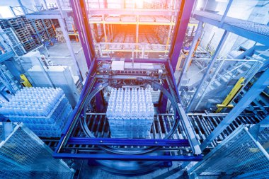 İçecek fabrikasında ambalaj hattı için modern bağlama ve taşıma makinesi.