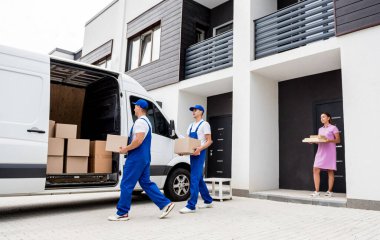 İki nakliye şirketi çalışanı bir minibüse kutu yüklüyorlar..