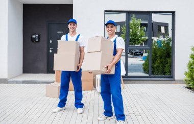 İki nakliye şirketi çalışanı bir minibüse kutu yüklüyorlar..