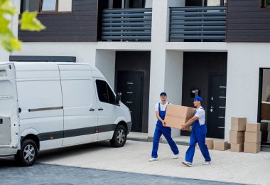 İki nakliye şirketi çalışanı bir minibüse kutu ve mobilya yüklüyorlar..