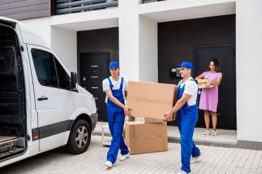 İki nakliye şirketi çalışanı bir minibüse kutu yüklüyorlar..
