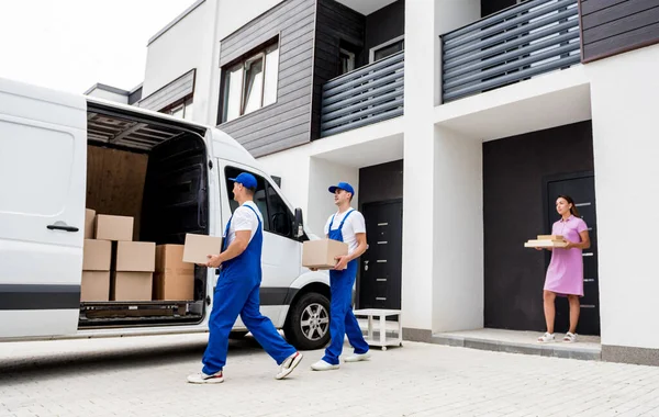 İki nakliye şirketi çalışanı bir minibüse kutu yüklüyorlar..