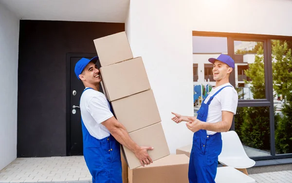 Zwei Mitarbeiter einer Umzugsfirma laden Kisten in einen Kleinbus. — Stockfoto