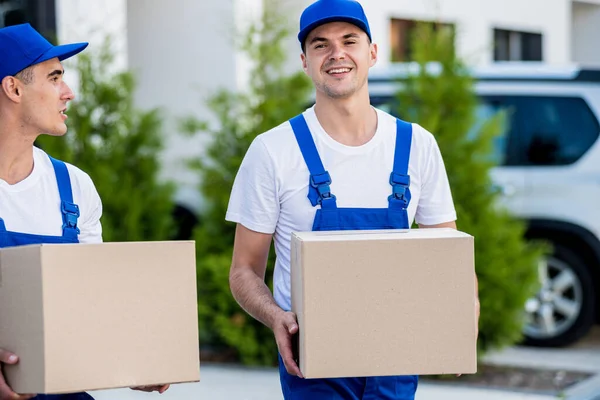 Zwei Mitarbeiter einer Umzugsfirma laden Kisten in einen Kleinbus. — Stockfoto