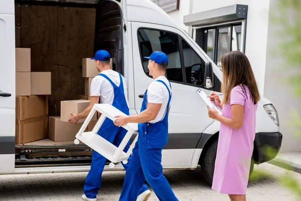 Dos trabajadores de la empresa de mudanzas están cargando cajas en un minibús. — Foto de Stock