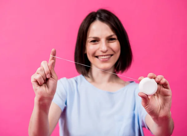 Beautiful young woman use dental floss on pink background — Stock Photo, Image
