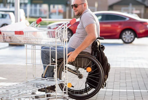 Persona con una discapacidad física empujando carro delante de sí mismo en el estacionamiento del supermercado —  Fotos de Stock