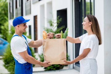 Genç kurye evde genç bir bayana mal getiriyor.