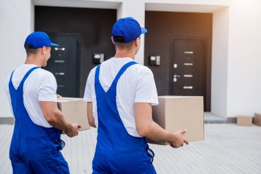 İki nakliye şirketi çalışanı minibüsten yeni eve kutular boşaltıyor.