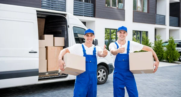 Zwei Mitarbeiter einer Umzugsfirma laden Kisten aus Kleinbus in neues Zuhause — Stockfoto