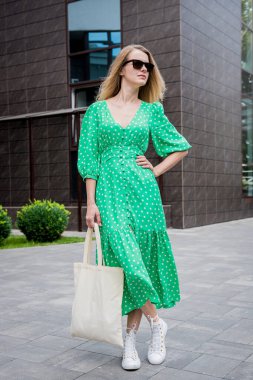 Şehrin arka planında keten rengi bir çantası olan güzel bir kadın..