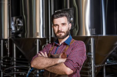 Modern bira fabrikasında deri önlüklü genç bir bira imalatçısı.