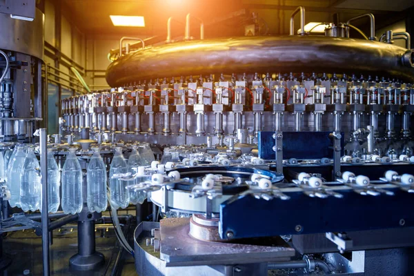 Modern içecek fabrikasında otomatik doldurma makinesi plastik PET şişelerine su doldurur.