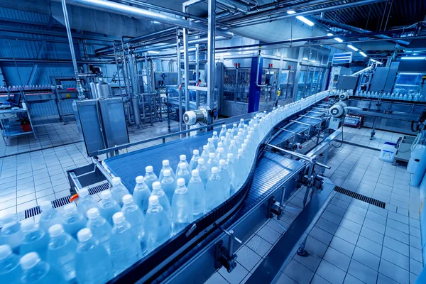 Конвеєрний пояс з пляшками питної води на сучасному заводі напоїв . — стокове фото