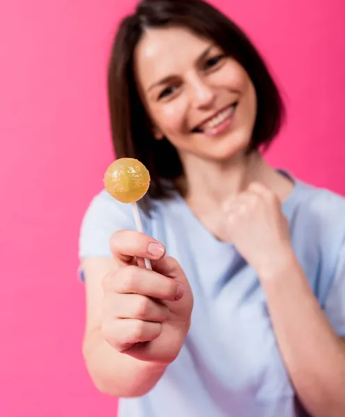 Jovem com dentes sensíveis comendo pirulito doce no fundo de cor — Fotografia de Stock