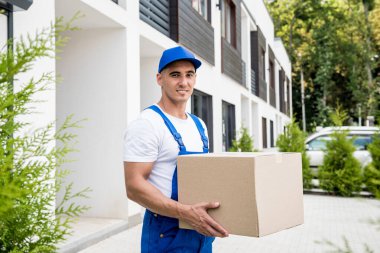 Genç teslimatçı elinde bir karton kutu tutuyor.