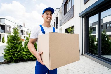 Genç teslimatçı elinde bir karton kutu tutuyor.