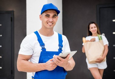 Genç kurye evde genç bir bayana mal getiriyor.