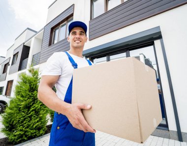 Genç teslimatçı elinde bir karton kutu tutuyor.