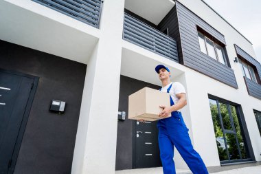 Genç teslimatçı elinde bir karton kutu tutuyor.