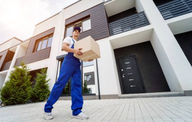 Genç teslimatçı elinde bir karton kutu tutuyor.