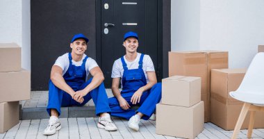 İki nakliye şirketi çalışanı merdivende otururken mola veriyor.