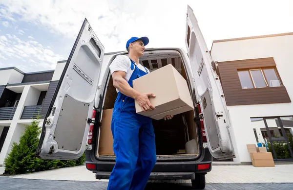Two removal company workers unloading boxes and furniture from minibus — Stock Photo, Image