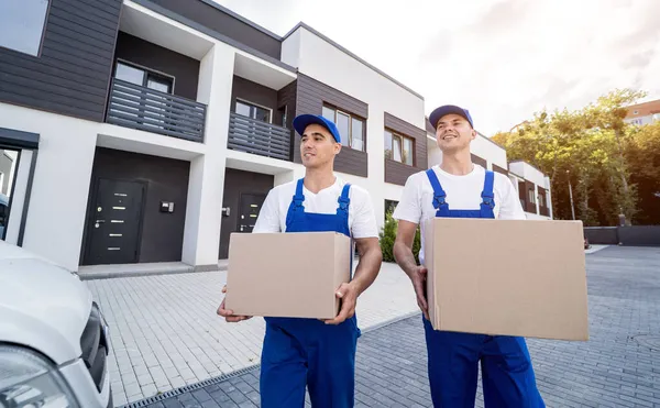 Zwei Mitarbeiter einer Umzugsfirma laden Kisten und Möbel in einen Kleinbus. — Stockfoto